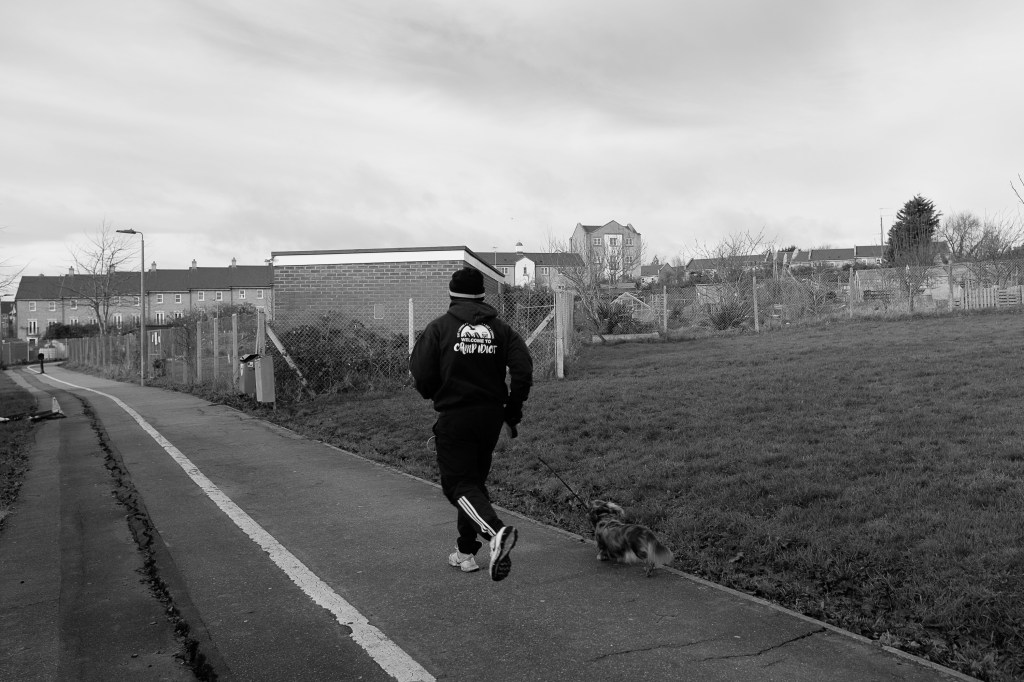 A jogger and his small dog trying to keep up