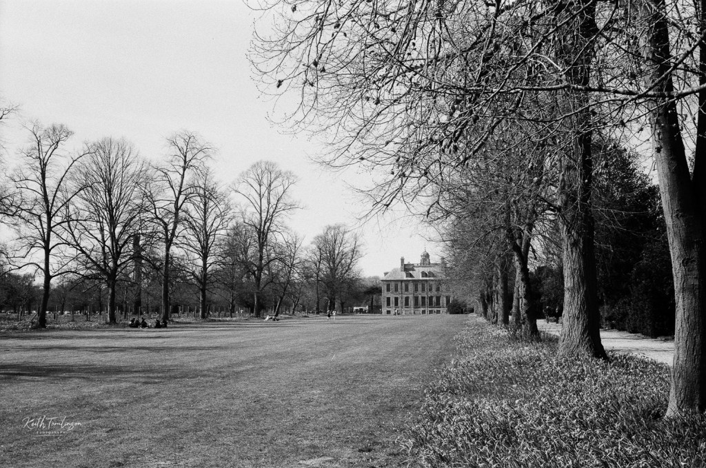 A black and white photo of the lawn leading to Belton House