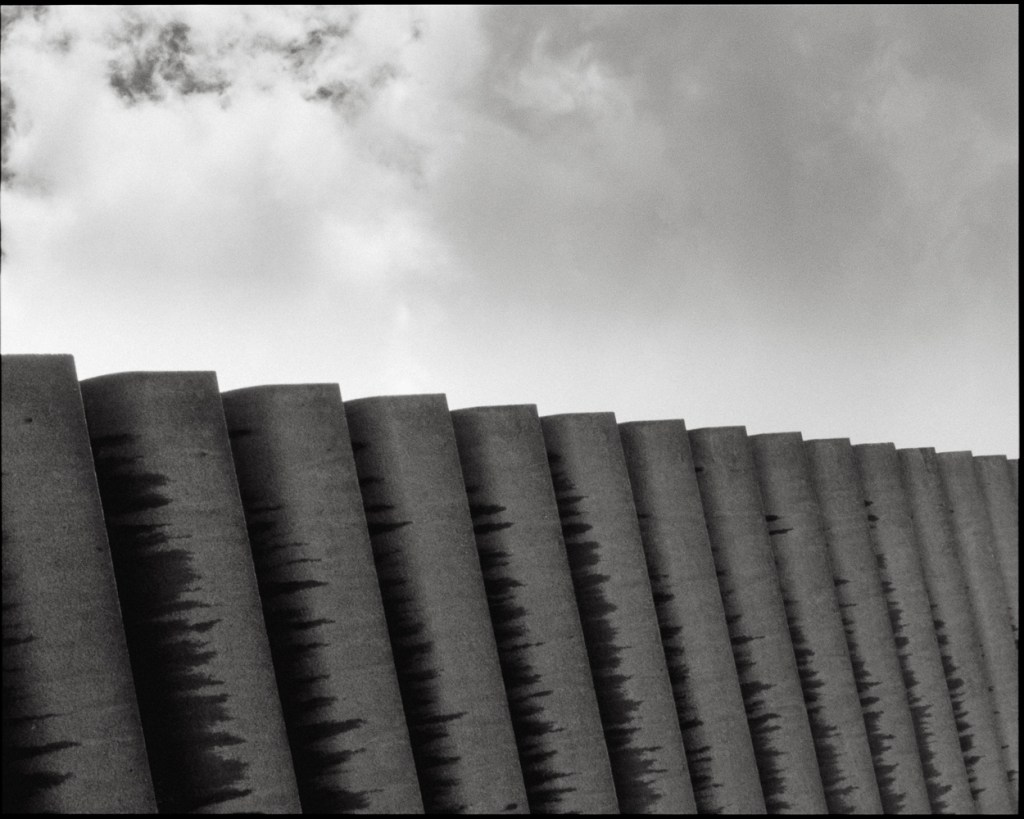 An image of concrete fins across a  black and white cloudy sky