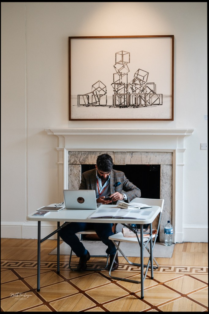A photo dealer looks at his phone whilst waiting for interested customers at Photo London
