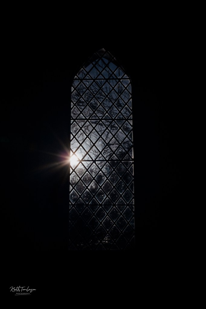 The bright winter sun shines through a Victorian church window